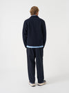 Rear view of a model wearing the Navy Wool Fleece Uniform Jacket in a studio setting with a light backdrop. The image displays the plain back construction, shoulder seams, and dark navy wool fleece fabric texture.