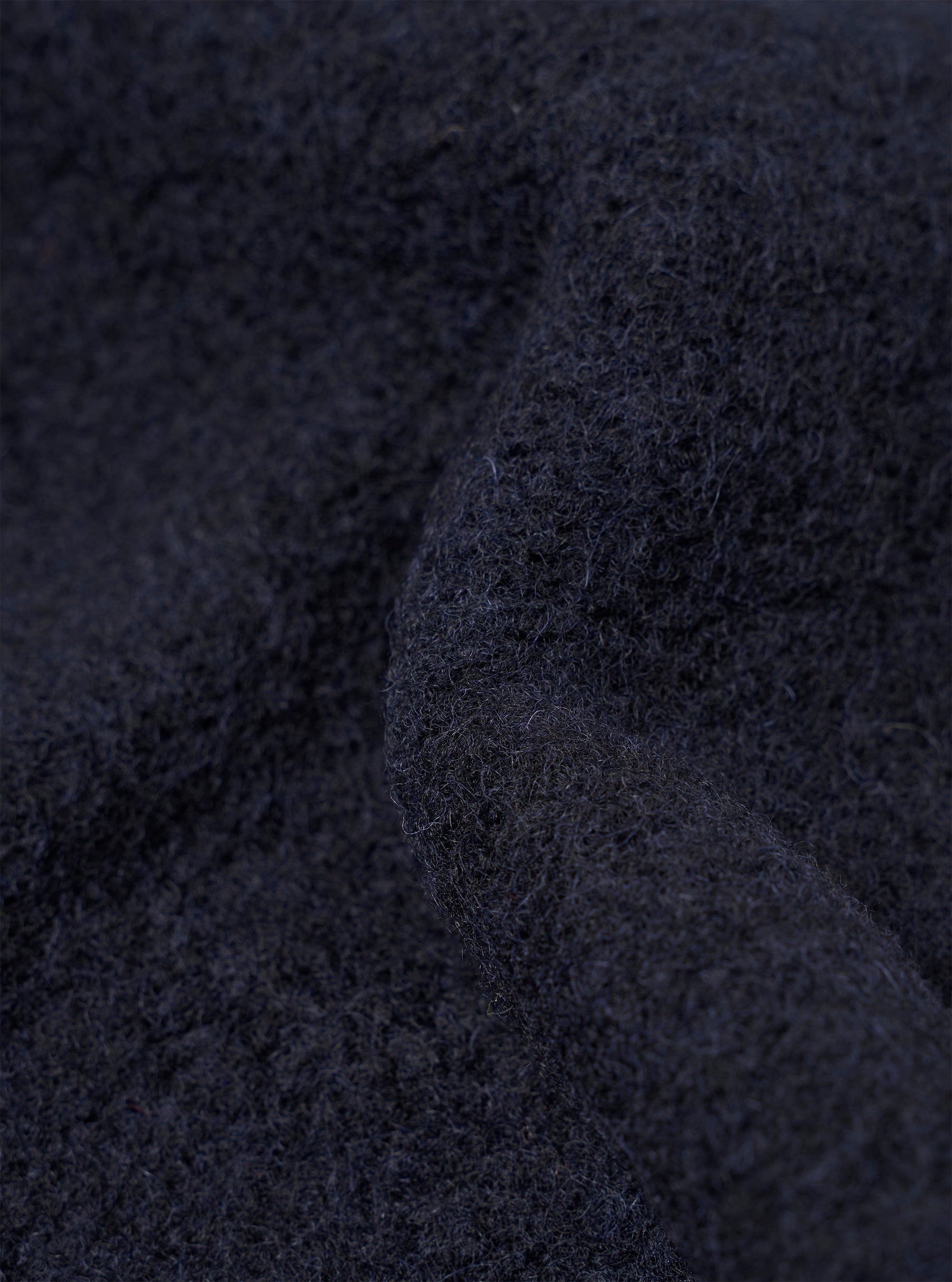 Close-up detail shot of a navy wool fleece fabric, showing a heavily brushed, fluffy texture with fine fibres across the surface. The deep navy tone varies slightly where the fabric folds, revealing the dense, soft pile. No background is visible.
