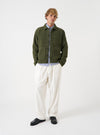 Front view of a model wearing the Olive Wool Fleece Uniform Jacket set against a plain light studio background. The model faces front, highlighting the olive green wool fleece fabric, classic collar, and patch pocket details.