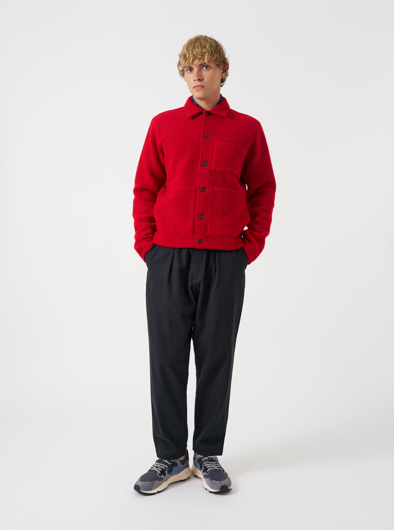 Front view of a model wearing the Scarlet Wool Fleece Uniform Jacket against a light studio backdrop. The bright red wool fleece jacket is shown from the front with its button placket, classic collar, and front patch pockets.