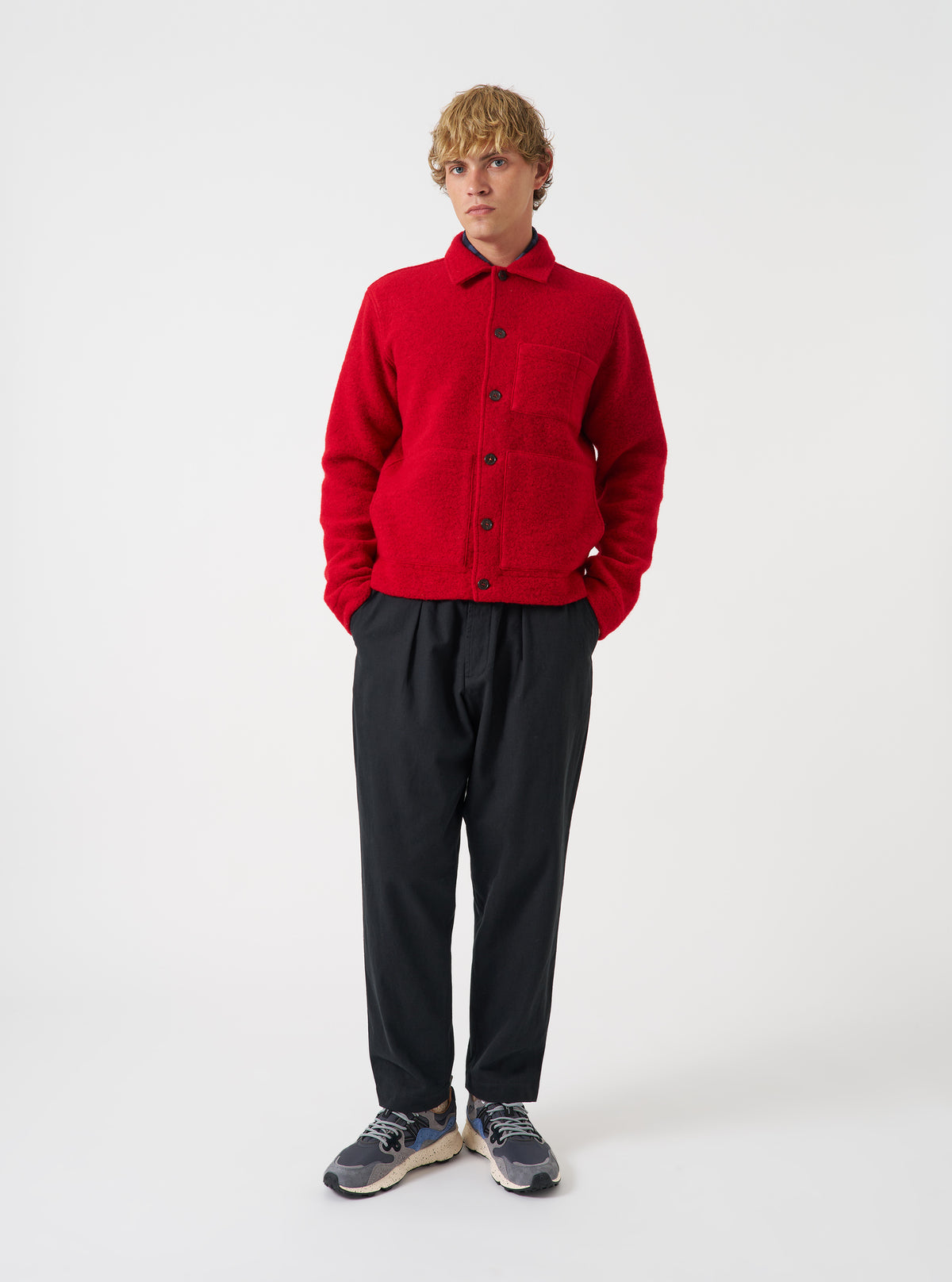 Front view of a model wearing the Scarlet Wool Fleece Uniform Jacket against a light studio backdrop. The bright red wool fleece jacket is shown from the front with its button placket, classic collar, and front patch pockets.