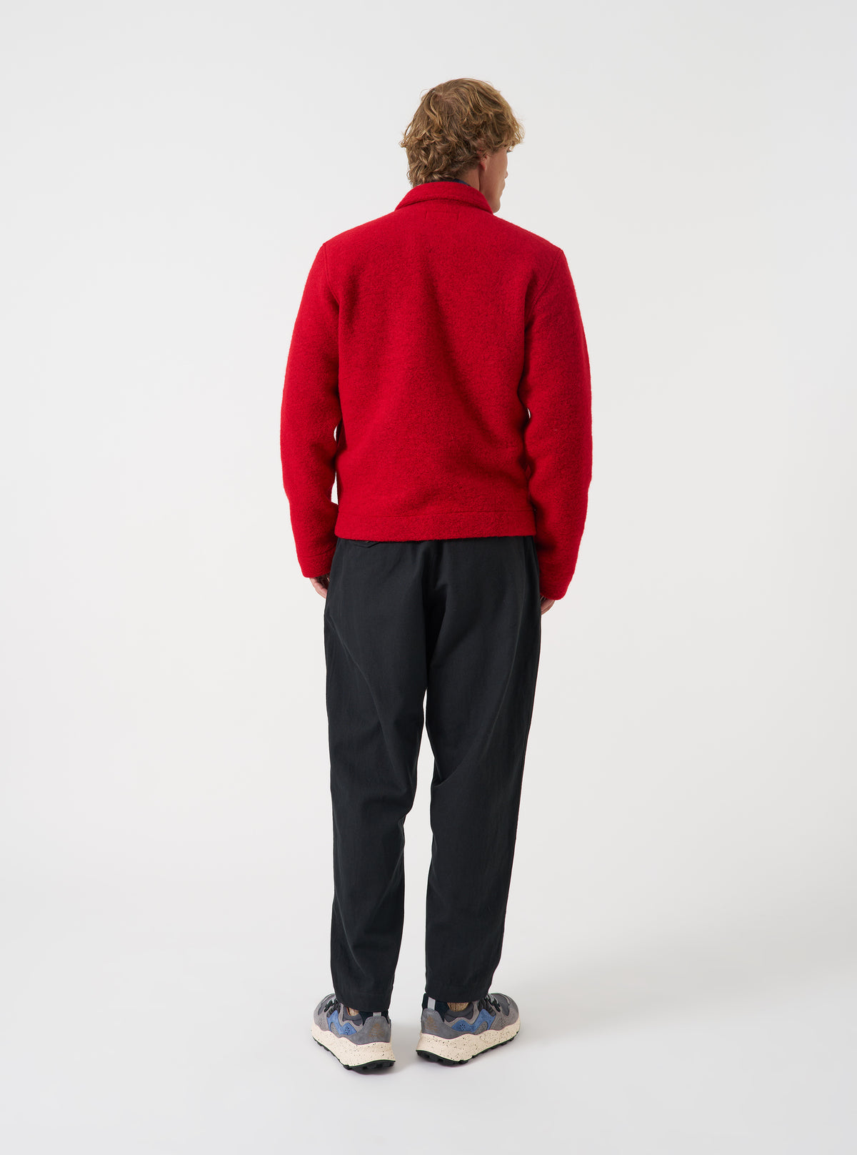 Rear view of a model wearing the Scarlet Wool Fleece Uniform Jacket against a simple light background. The image displays the back of the bright red fleece jacket, highlighting the relaxed fit and soft wool fleece texture.