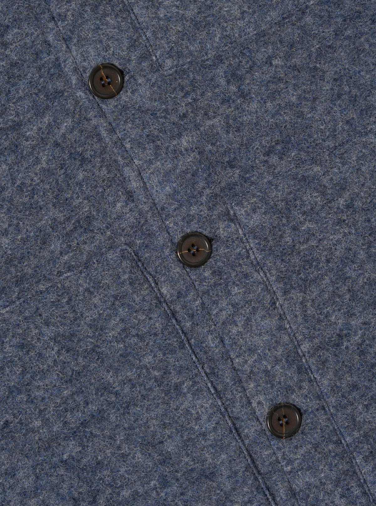 Close-up of the Slate Blue Wool Fleece Uniform Jacket showing the texture of the wool fleece and the buttons. The jacket is on a flat surface.