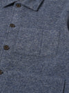 Close-up of the slate blue wool fleece uniform jacket showing the texture, buttons, and pocket. The jacket is on a flat surface.