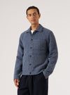 A man poses in front of a white background, wearing a Slate Blue Wool Fleece Uniform Jacket. The jacket is buttoned and he has his hand in his pocket.