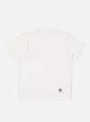 Flat lay of an Ecru Single Jersey Core Tee on a white background. The tee is a light cream color and has a relaxed fit. A small tag is visible near the hem.