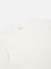 Close-up of the Ecru Single Jersey Core Tee on a white background. The soft, neutral color and smooth fabric are highlighted. The brand label is visible at the neck.
