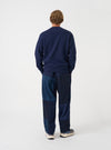 Angled view of a model wearing the Navy Brush Back Sweat Core Sweatshirt in a plain studio setting. The shot demonstrates the garment fit from the side, highlighting the sleeve length and soft brushed cotton texture.