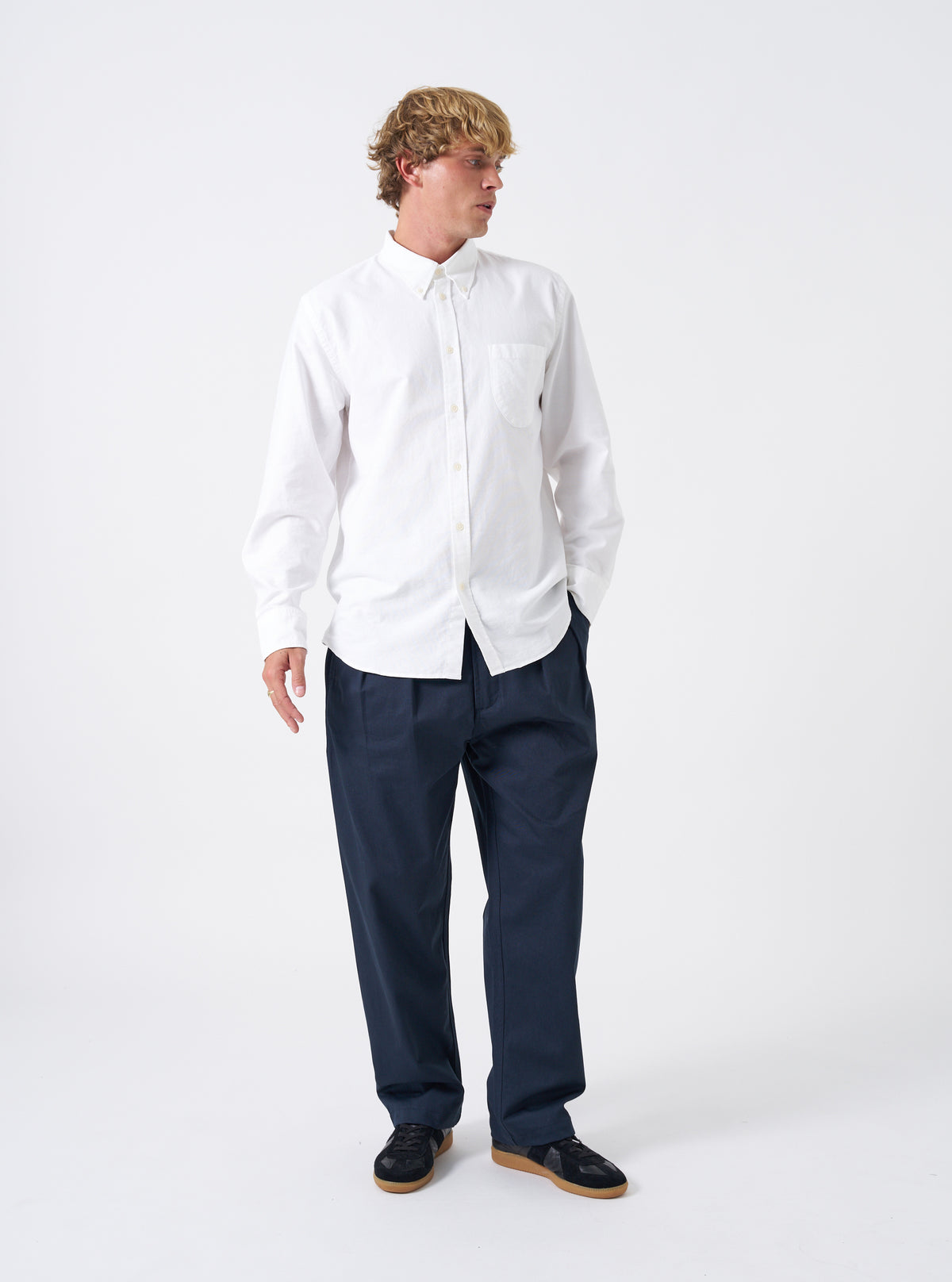 Front view of a model wearing the White Oxford Daybrook Shirt in a bright studio environment. The model faces forward, demonstrating how the classic white button-down shirt fits across the torso, arms, and collar area.