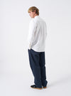Side angled view of a model wearing the White Oxford Daybrook Shirt against a light backdrop. The image emphasizes the tailored fit along the body, sleeve cuffing, and clean style of the organic cotton shirt.