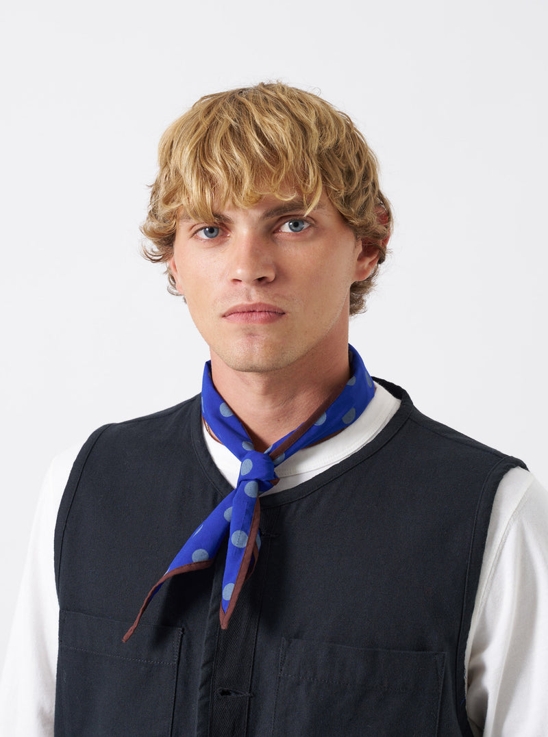 A model wearing the Blue Bold Dot Print Rayon Scout Scarf in a studio setting with a plain background. The scarf features a navy blue base with prominent white polka dots tied neatly around the neck.