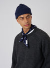 A model on a white background wears a Navy Bold Dot Print Rayon Scout Scarf tied around his neck with a gray sweater and navy beanie.