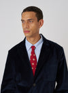 A model wears a Red Bold Dot Print Rayon Tie with a blue striped shirt and navy blazer against a white background.