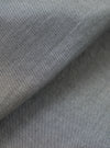 Close-up of the chambray fabric on the Black Prince Daybrook Shirt. The woven textile shows a fine two-tone grey and white yarn weave typical of chambray. A folded edge runs diagonally across the frame, revealing a soft brushed inner lining in a darker grey tone.