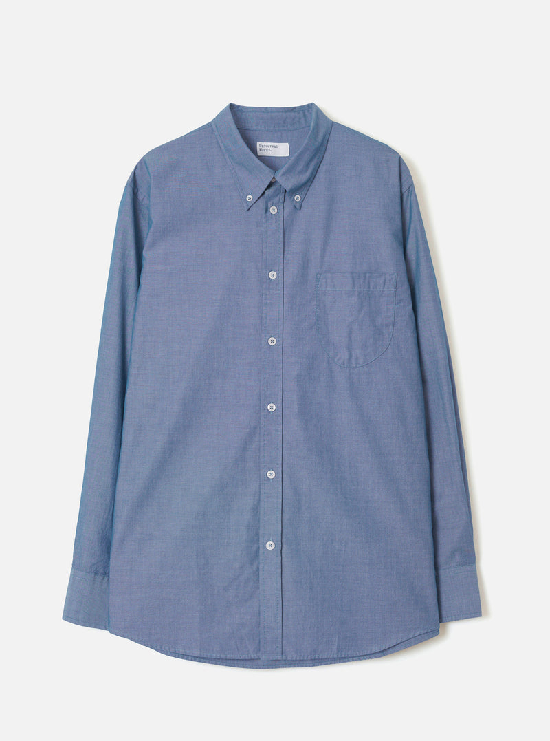 Front view of the Indigo Prince Chambray Daybrook Shirt laid flat on a light grey studio backdrop. Features a spread collar, full button placket with white buttons, a single chest patch pocket, and long sleeves with buttoned cuffs.