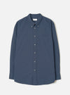 Front view of the Navy Prince Chambray Daybrook Shirt laid flat on a light grey studio backdrop. Features a spread collar, full button closure down the front, single chest patch pocket, and long sleeves with buttoned cuffs. No model present.
