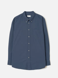 Front view of the Navy Prince Chambray Daybrook Shirt laid flat on a light grey studio backdrop. Features a spread collar, full button closure down the front, single chest patch pocket, and long sleeves with buttoned cuffs. No model present.