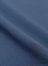 Close-up of navy blue chambray fabric, showing a plain weave texture with a subtle two-tone woven finish. The cloth is folded to create a diagonal ridge across the frame, with soft shadows highlighting the fabric weight and drape. No garment details or background are visible.