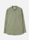 Olive chambray long-sleeve shirt laid flat on a light grey background. Button-down collar with collar buttons visible, full button placket with five cream buttons, single chest patch pocket on the left, buttoned cuffs, and a curved hem. Fine woven texture throughout. Universal Works woven label at the neck.