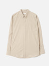 Sand chambray Daybrook shirt laid flat on a white studio backdrop. Button-down collar with tonal buttons down the placket, a single patch pocket on the left chest, long sleeves with plain cuffs, and a curved hem. Plain weave fabric in a warm sand tone.