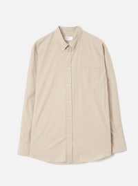 Sand chambray Daybrook shirt laid flat on a white studio backdrop. Button-down collar with tonal buttons down the placket, a single patch pocket on the left chest, long sleeves with plain cuffs, and a curved hem. Plain weave fabric in a warm sand tone.