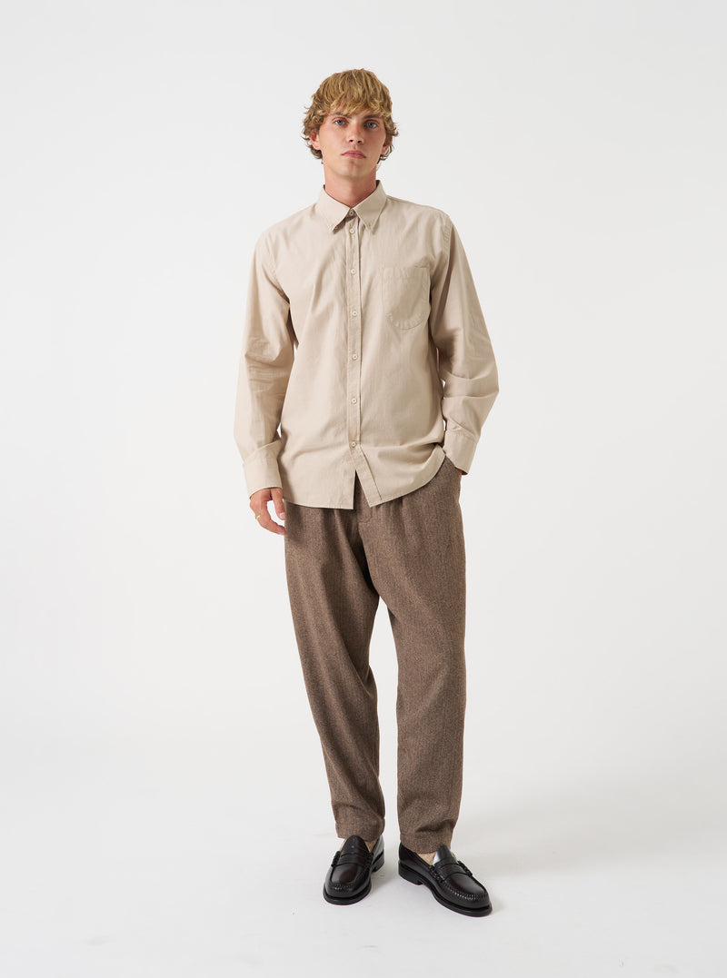 A male model poses against a plain light grey backdrop wearing the Sand Prince Chambray Daybrook Shirt. The button-down shirt features a chest pocket and point collar, buttoned up at the front.