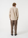 Back view of a male model wearing the Sand Prince Chambray Daybrook Shirt against a plain studio background. The light tan cotton fabric features a visible back yoke, neat shoulder seams, and a relaxed straight fit.