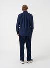 Angled view of a model wearing the Navy Prince Chambray Daybrook Shirt against a simple studio backdrop. Highlights the overall fit, sleeve cut, buttoned cuffs, and fine navy prince chambray cotton fabric.