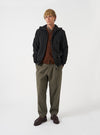 Front view of a model wearing the Black Brush Back Sweat Core Hoody in a plain studio setting. The model is shown wearing the black hooded sweatshirt with attached hood, drawstring details, relaxed fit, and front pouch pocket.