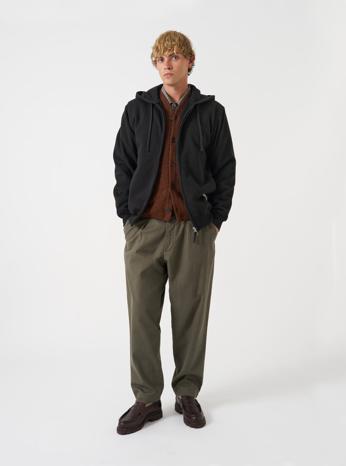 Front view of a model wearing the Black Brush Back Sweat Core Hoody in a plain studio setting. The model is shown wearing the black hooded sweatshirt with attached hood, drawstring details, relaxed fit, and front pouch pocket.