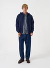 Front view of a model wearing the Navy Brush Back Sweat Core Hoody in a minimalist studio environment. The model faces forward, presenting the dark navy cotton hooded sweatshirt with its front pocket and relaxed casual fit.