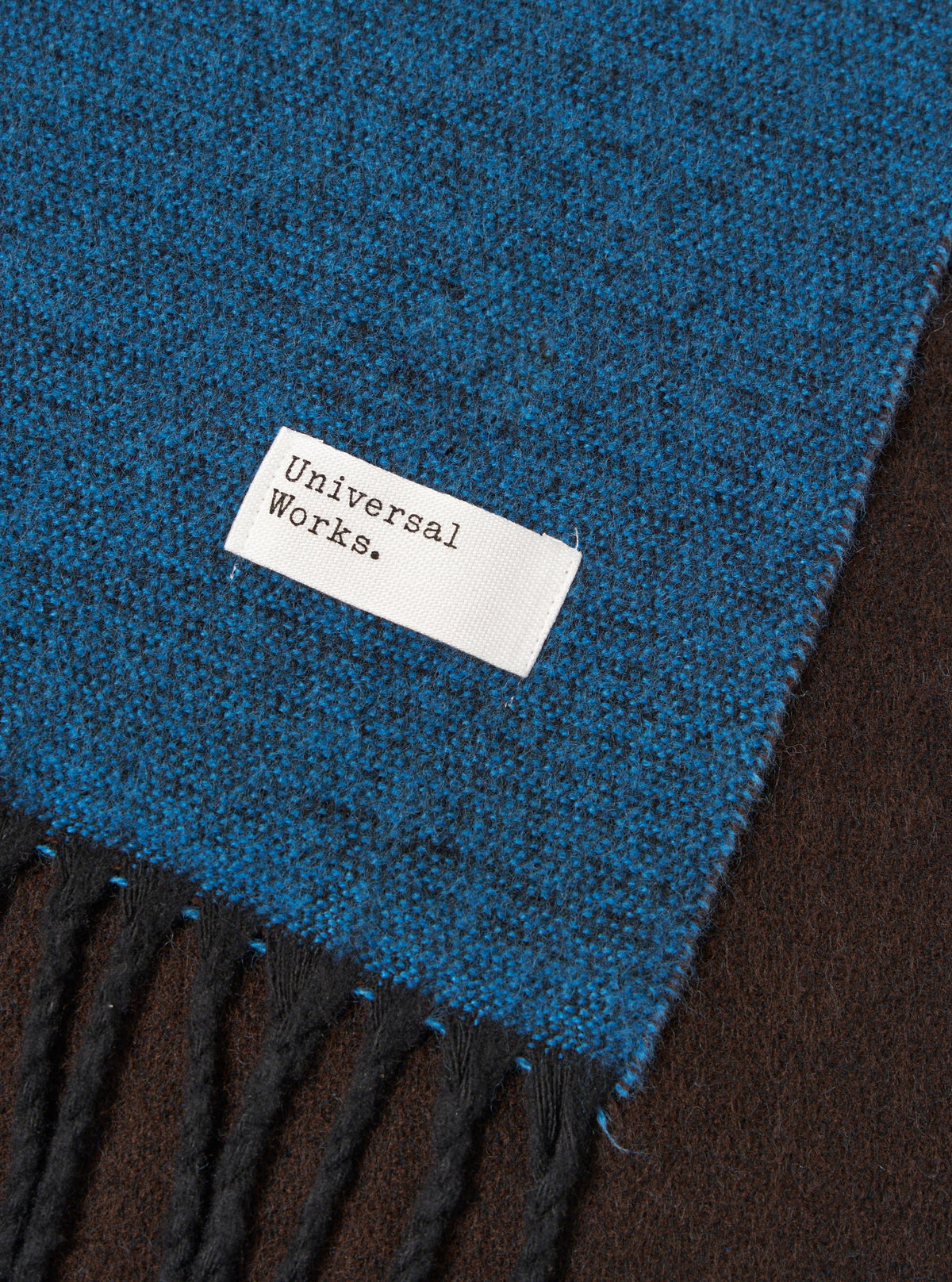 Draped view of the Light Blue/Brown Double Sided Scarf shown against a clean studio backdrop. The photo highlights how the light blue and brown fabric layers fold together, emphasizing the soft texture and subtle fringed trim.
