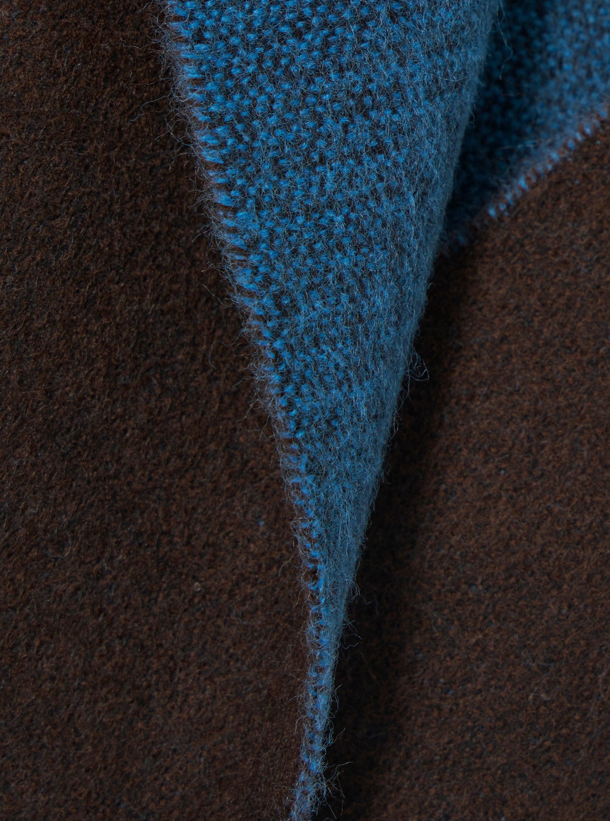Extreme close-up fabric swatch image of the Light Blue/Brown Double Sided Scarf. The close shot captures the distinct contrast between the light blue and brown woven fibers, emphasizing the soft tactile finish of the material.