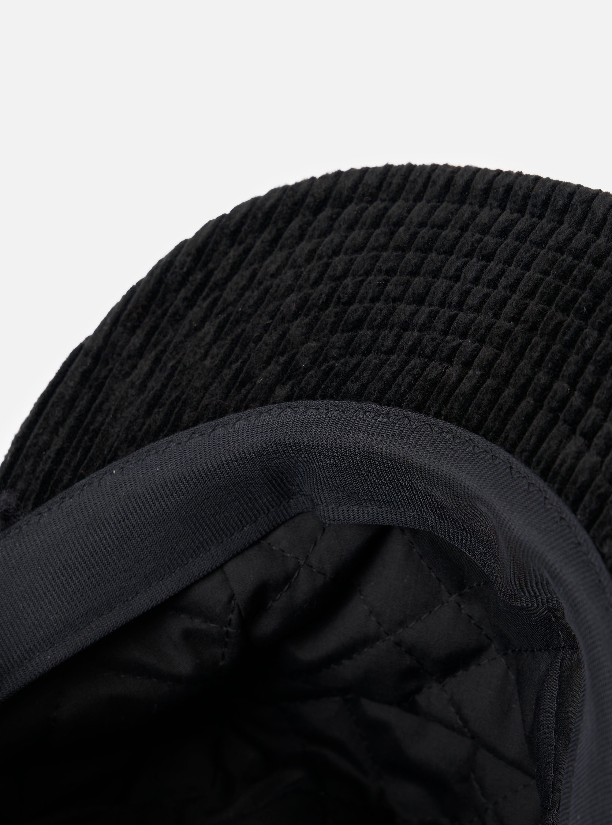 Close-up of the inside of the cableami® Black Corduroy 5w Cap, showing the quilted lining and corduroy texture against a plain white background.