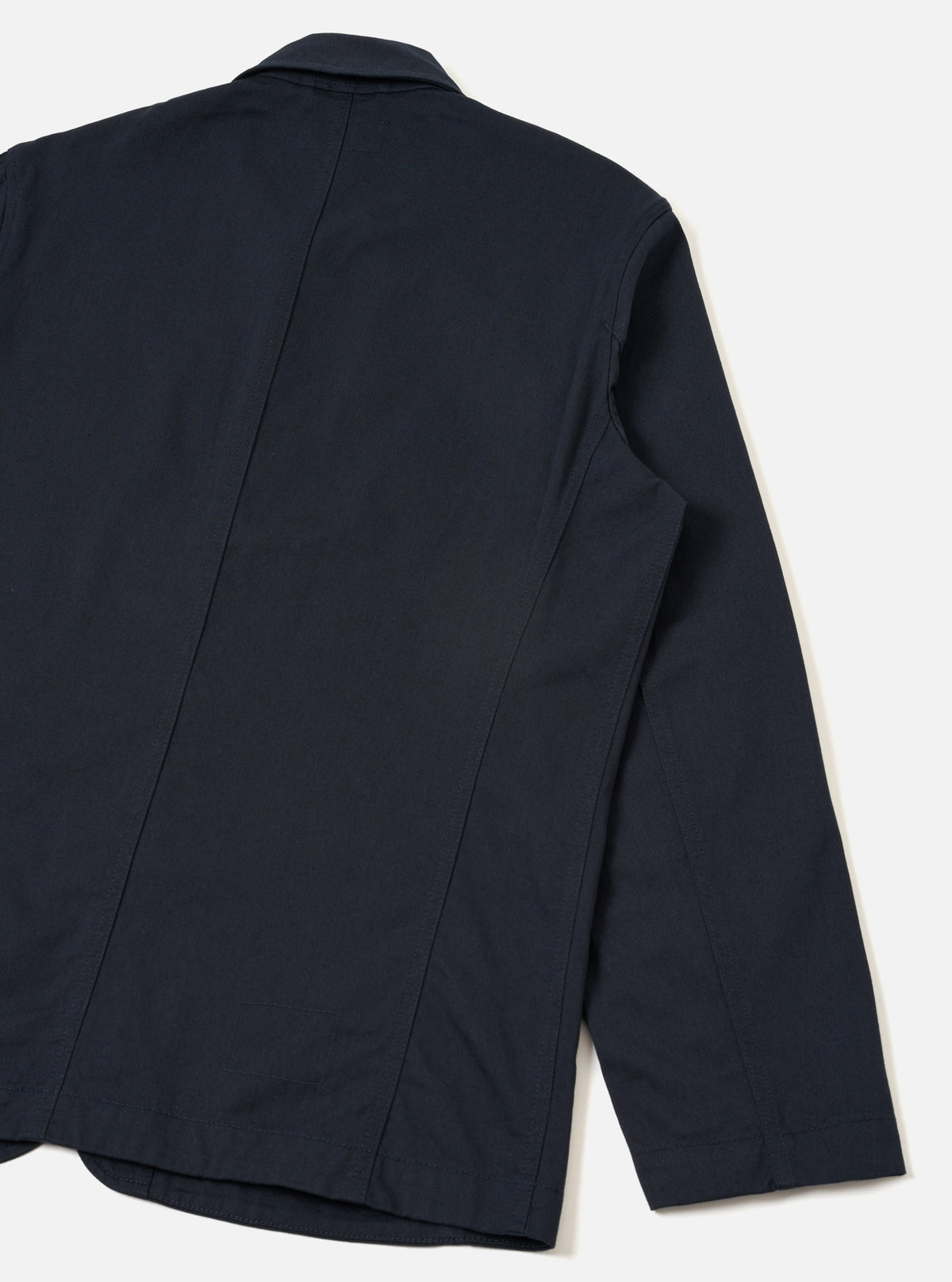 Back view of the Navy Twill Bakers Chore Jacket displayed against a plain white background. Highlights the clean dark navy twill cotton fabric, straight hemline, and simple seam detailing across the back.