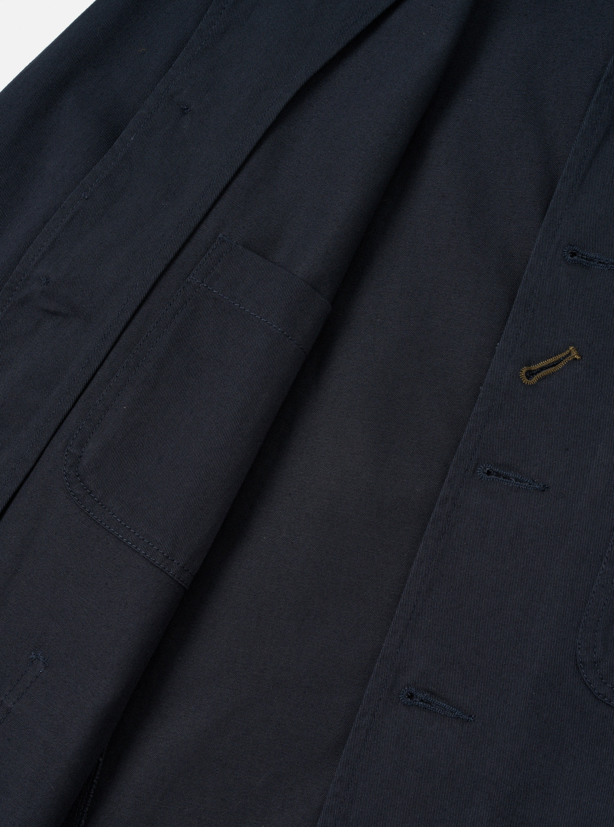 Close-up detail shot of the Navy Twill Bakers Chore Jacket against a plain white background. Focuses on the button placket, signature diagonal buttonhole, collar, and chest pocket on dark navy twill.