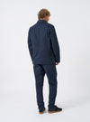 Rear view of a model wearing the Navy Twill Bakers Chore Jacket in a light studio setting. The model stands facing away from the camera, demonstrating the fit across the shoulders and overall back length.