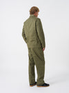 Angled side view of a model wearing the Light Olive Twill Bakers Chore Jacket in a bright studio setting. Shows the jacket fit along the sleeves, shoulder seams, and side profile in light olive green twill.