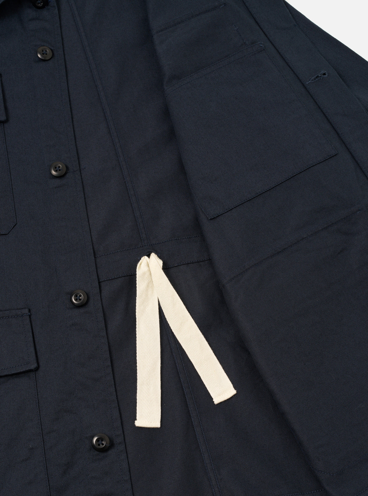 Close-up detail shot of the front flap pocket and hidden button closure on the Navy Twill MW Fatigue Jacket. Displays the dark navy cotton twill weave, neat topstitching, and pocket flap design.