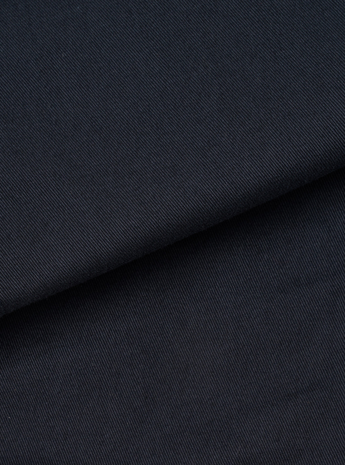 Extreme close-up fabric swatch image showcasing the texture of the Navy Twill MW Fatigue Jacket. Highlights the tight diagonal weave pattern, durable finish, and rich dark navy shade of the twill.