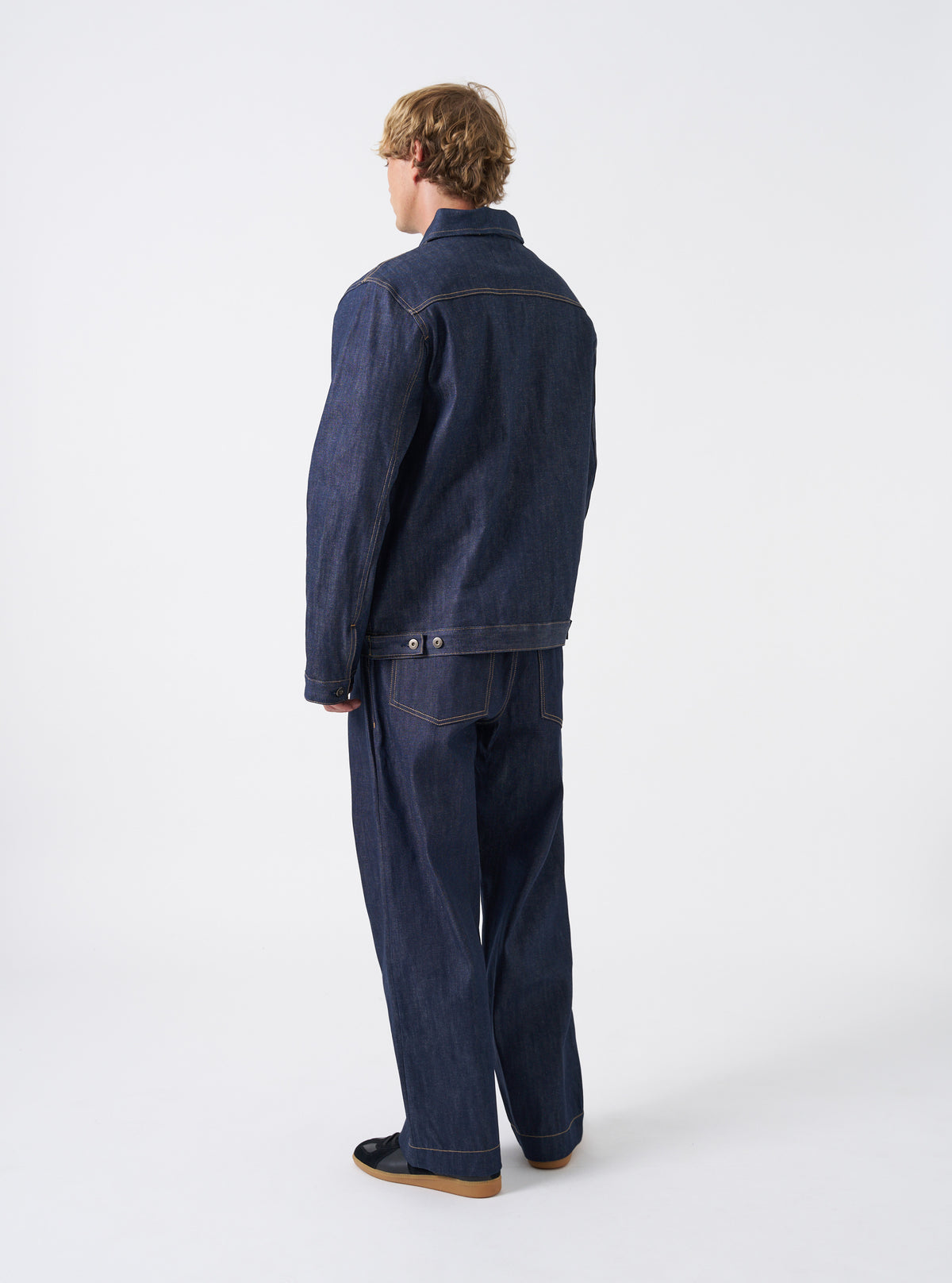 Back perspective of the Indigo 13oz Selvedge Denim Bakers Chore Jacket set on a white background, focusing on the structured back seams, clean hem, and deep dark blue selvedge denim texture.