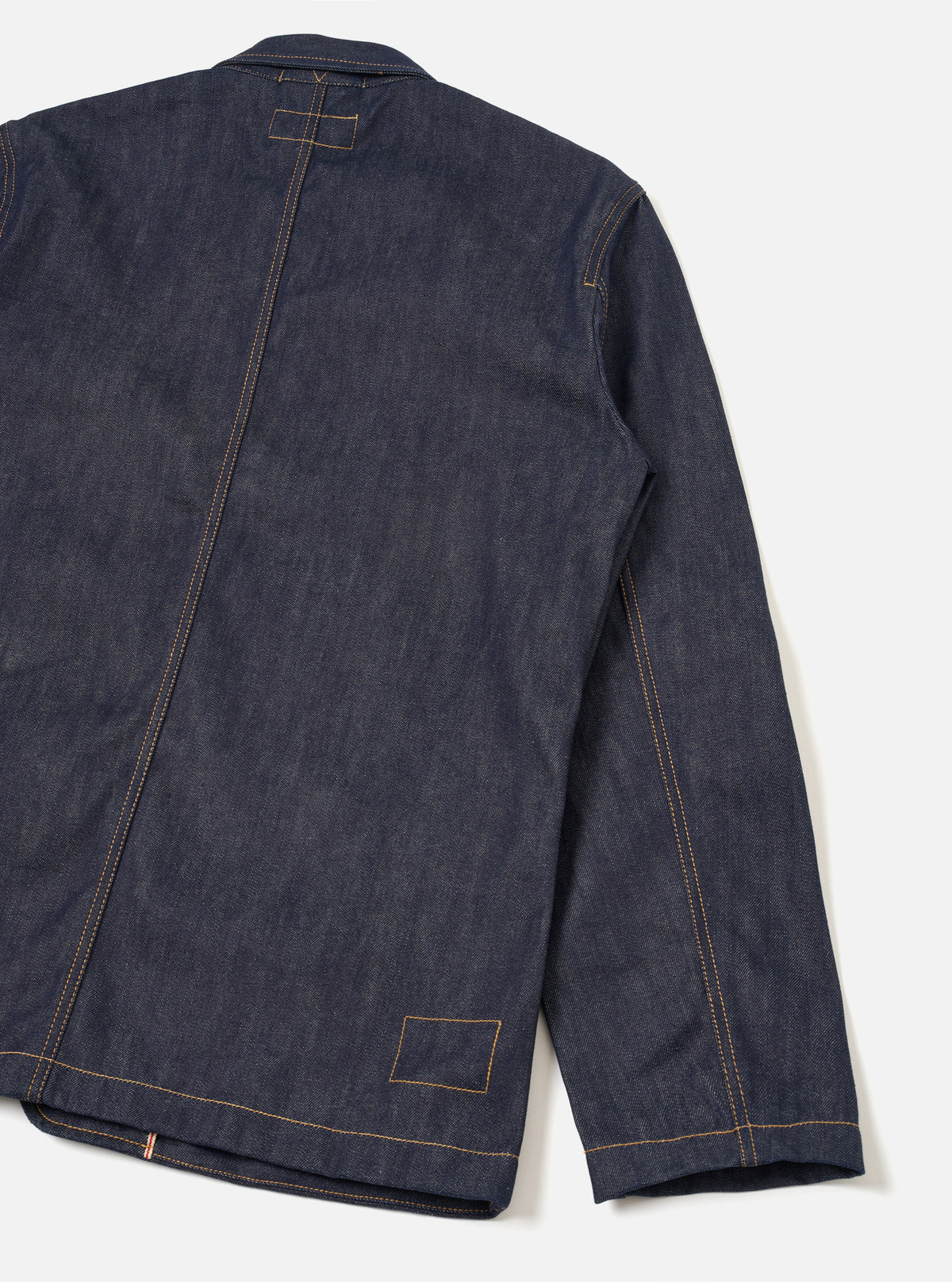 Rear view of the Indigo 13oz Selvedge Denim Bakers Chore Jacket displayed against a plain background, showing the back paneling, shoulder seams, neat hemline, and deep indigo denim fabric.