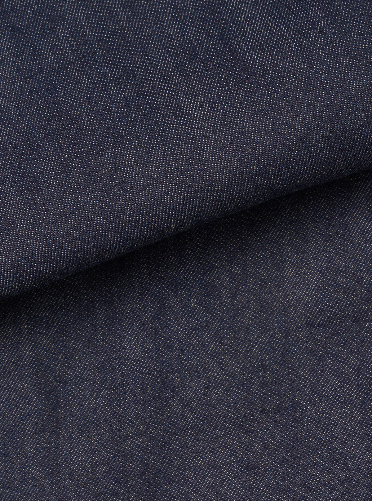 Close-up fabric swatch image of the Indigo 13oz Selvedge Denim Bakers Chore Jacket against a plain studio backdrop, demonstrating the diagonal twill texture and rich deep indigo coloring.
