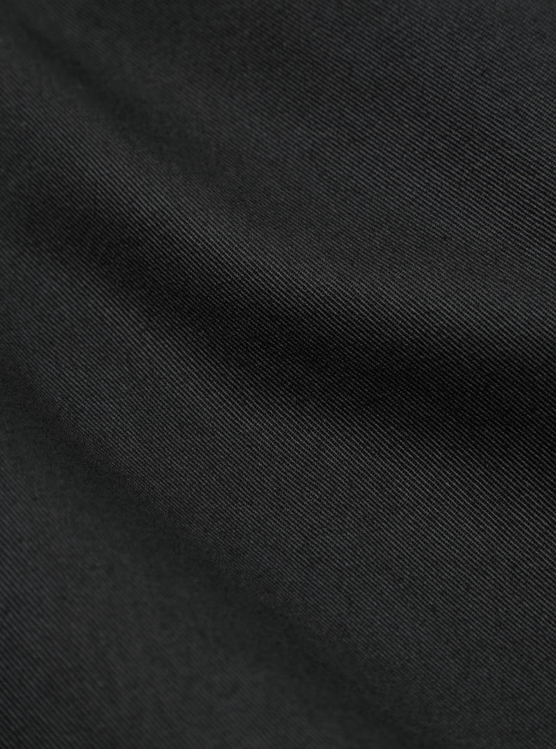 Close-up of the Black Twill Curved Pant, showing the fabric's texture and drape. The twill weave is visible, creating a subtle pattern. 