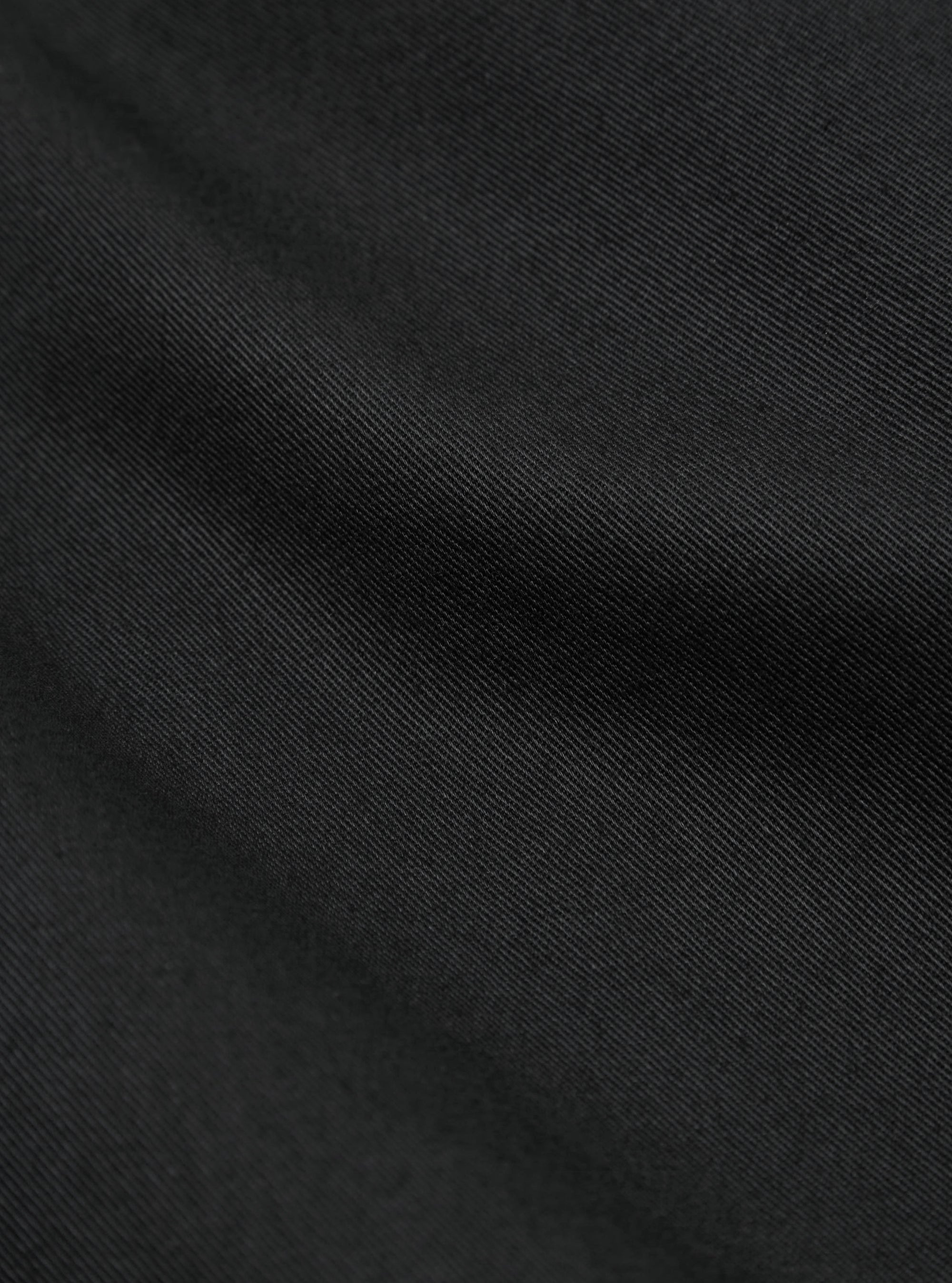 Close up on the black twill fabric of the London Jacket. The material has a subtle diagonal weave pattern.