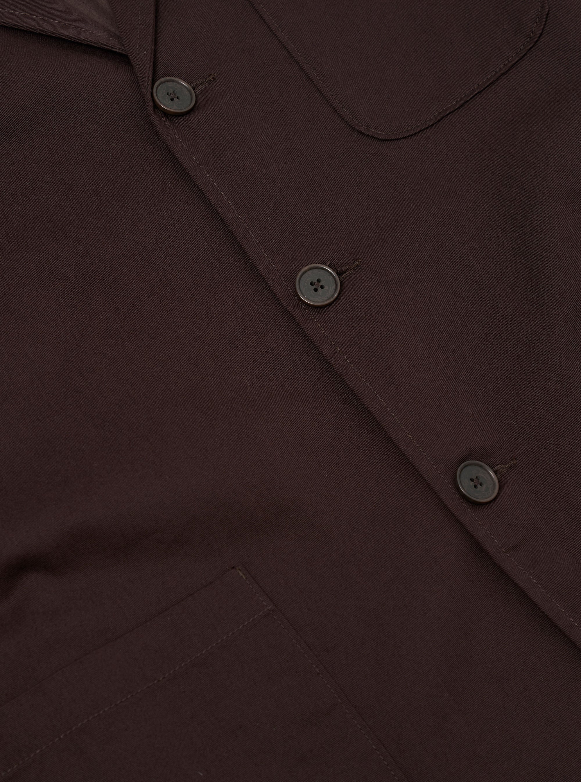 The Brown Twill Three Button Jacket is shown from the back, displayed flat against a plain white background. The image highlights the jacket's clean construction, featuring a central seam and a single vent at the hem.