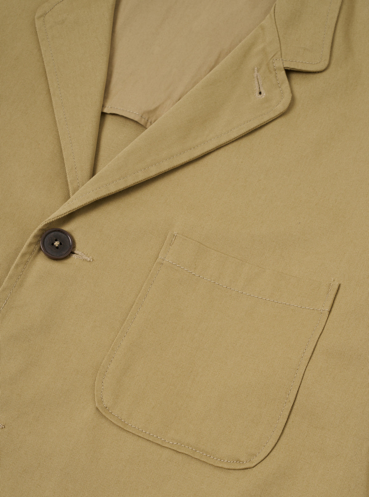 Front view of the Sand Twill Three Button Jacket displayed against a plain off-white background. Features three front buttons, notch lapels, structured chest, and front patch pockets.