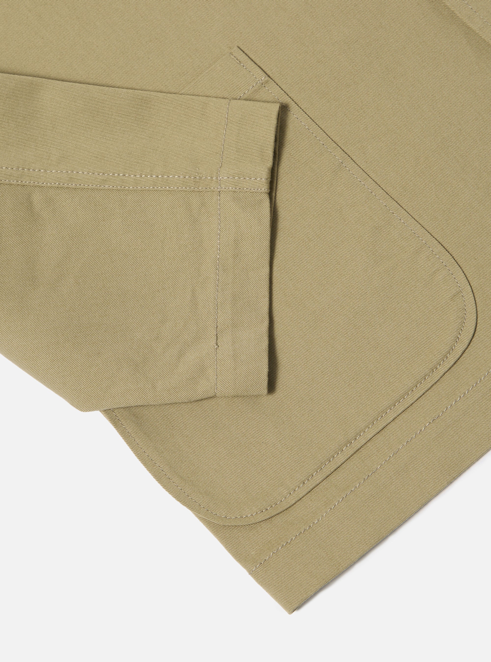 Close-up of the sand twill three button jacket showing the sleeve and rounded edge of the jacket on a white background.