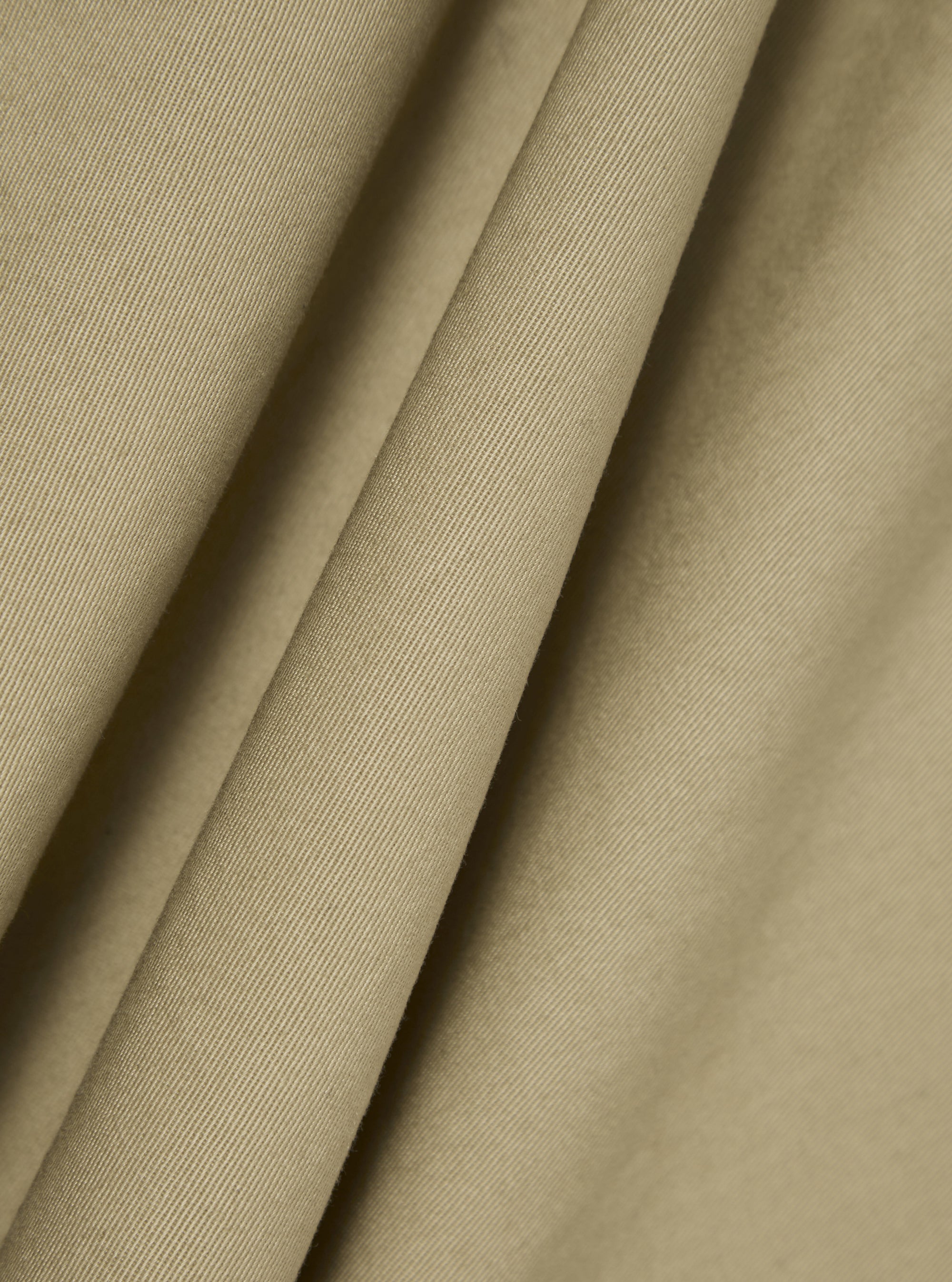Close-up of the sand twill fabric of the Kyoto Work Jacket, showing the texture and color. The material is draped to highlight its quality.