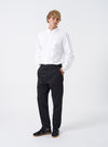 Full front shot of a model wearing the Black Twill Military Chino on a clean white background. The model wears the black trousers paired with casual shoes, demonstrating the comfortable mid-rise fit and neat taper toward the ankles.